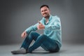 Appealing casual young man sitting on the floor, looking to the camera smiling Royalty Free Stock Photo