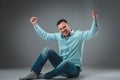 Appealing casual young man sitting on the floor, looking to the camera smiling Royalty Free Stock Photo