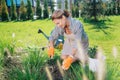 Appealing family woman sitting on her knees while grubbing up weeds