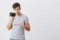 Appealing, muscular, confident male posing indoors against gray background. Stylish handsome guy with trendy haircut Royalty Free Stock Photo