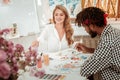 Appealing stylish art teacher feeling joyful painting with her student