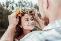 Loving bearded man putting beautiful floral chaplet on head of his appealing woman