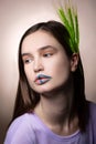Appealing woman with blue lines on lips and green spikelet in hair