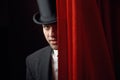 Appearing handsome man magician peeking out from behind stage drapery curtain Royalty Free Stock Photo