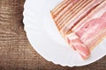 Appetiser from slices of bacon on plate on wooden plank Royalty Free Stock Photo