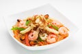 Appetising cellophane noodles with seafood in a white plate, close up on a white background