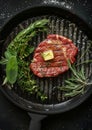 Appetite: Big beef steak, perfectly roasted with rosemary herbs and pepper, sizzling on a cast iron grill pan. Enhanced with Royalty Free Stock Photo