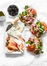 Appetizer, aperitif, snack table - gorgonzola, brie cheese, dried olives, apple, almonds and prosciutto, tomatoes, green salad