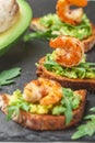 Appetizer of bread with seeds, shrimp, avocado and arugula