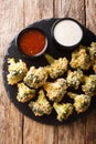 Appetizer of breaded broccoli baked with parmesan served with sauces. Vertical top view