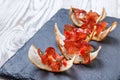 Appetizer bruschetta with jerky prosciutto on thinly sliced ciabatta bread on stone slate background close up.