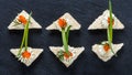 Appetizer canape with red caviar and cream cheese on stone slate background close up.