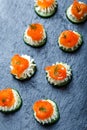 Appetizer canape with salmon, cucumber and cream cheese on stone slate background close up. Royalty Free Stock Photo