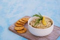 Appetizer, fish pate from mackerel, boiled eggs and onions in a white ceramic bowl on a blue concrete background. Served with Royalty Free Stock Photo