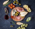 Appetizer, italian antipasto, ham, olives, cheese, bread, grapes, pear and glass of wine on dark stone background. Royalty Free Stock Photo