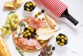 Appetizer, italian antipasto, ham, olives, cheese, bread, grapes, pear and wine on white wood background. Royalty Free Stock Photo