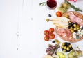 Appetizer, italian antipasto, ham, olives, cheese, bread, grapes, pear and wine on white wood background Royalty Free Stock Photo