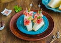 Appetizer, melon with prosciutto on a blue plate on a brown wooden background. Snack recipes