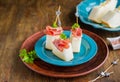 Appetizer, melon with prosciutto on a blue plate on a brown wooden background. Snack recipes