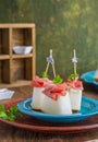 Appetizer, melon with prosciutto on a blue plate on a brown wooden background. Snack recipes