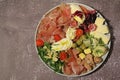 Appetizer plate, cold cuts, Parma ham, various types of cheese, olives, marinated onions, red tomatoes and tuna