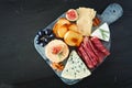 Appetizer platter with assorted cheeses and meats, overhead view on a dark stone background Royalty Free Stock Photo