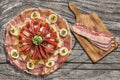 Appetizer Savory Dish Meze With Bacon Rashers On Cutting Board Set On Old Knotted Cracked Wooden Picnic Table