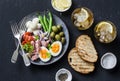 Appetizer table - plate of canned tuna, green beans, mozzarella cheese, tomatoes, boiled egg, olives, grilled bread and two glasse