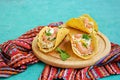 Appetizer, tacos with coleslaw salad, shrimp and corn tortilla sauce on a light wooden board on a turquoise concrete background
