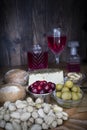 Appetizer time. Coconut wood tray with pistachios, green olives, cranberries, bread, goat cheese with herbs and rose wine Royalty Free Stock Photo