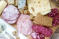 Appetizer of various types of sausages, meats, cheeses and crackers on a wooden board, served to wine