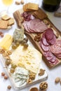 Appetizer of various types of sausages, meats, cheeses and crackers on a wooden board, served to wine