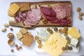 Appetizer of various types of sausages, meats, cheeses and crackers on a wooden board, served to wine