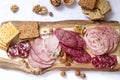 Appetizer of various types of sausages, meats, cheeses and crackers on a wooden board, served to wine