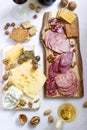 Appetizer of various types of sausages, meats, cheeses and crackers on a wooden board, served to wine