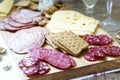 Appetizer of various types of sausages, meats, cheeses and crackers on a wooden board, served to wine