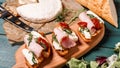 Appetizers table with italian antipasti snacks. Bruschetta with brie cheese, arugula and sun-dried tomatoes, ham. Food recipe