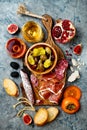 Appetizers table with italian antipasti snacks and wine in glasses. Charcuterie board over grey concrete background.