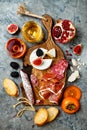 Appetizers table with italian antipasti snacks and wine in glasses. Charcuterie and cheese board over grey concrete background.
