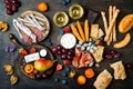 Appetizers table with italian antipasti snacks and wine in glasses. Cheese and charcuterie variety board over rustic wooden table