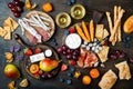 Appetizers table with italian antipasti snacks and wine in glasses. Cheese and charcuterie variety board over rustic wooden table