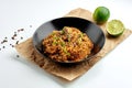 Appetizing Asian street food rice wok with pork, hot peppers, vegetables, cilantro, served in a black plate on a white plate. Royalty Free Stock Photo