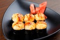 Appetizing baked hot sushi rolls. Set sushi on a black plate with ginger. Royalty Free Stock Photo