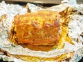 Appetizing baked piece of meat with a golden crust on silver foil