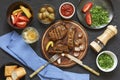 Appetizing barbecue steak at the dinner table in a restaurant with fresh vegetables, olives and wine. Italian Tradition Royalty Free Stock Photo