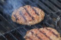 Appetizing beef hamburgers are roasting on BBQ grill with smoke Royalty Free Stock Photo