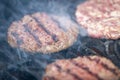 Appetizing beef hamburgers are roasting on BBQ grill with smoke Royalty Free Stock Photo