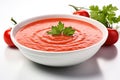 Appetizing bowl of vibrant red tomato soup with delightful assortment of fresh herbs beautifully arranged around it
