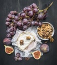 Appetizing camembert cheese, with walnuts, figs and a branch of ripe dark grapes, on a rustic wooden dark wooden background, top v Royalty Free Stock Photo