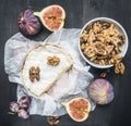 Appetizing camembert cheese, with walnuts, figs and a branch of ripe dark grapes, on a rustic wooden dark wooden background, top v Royalty Free Stock Photo